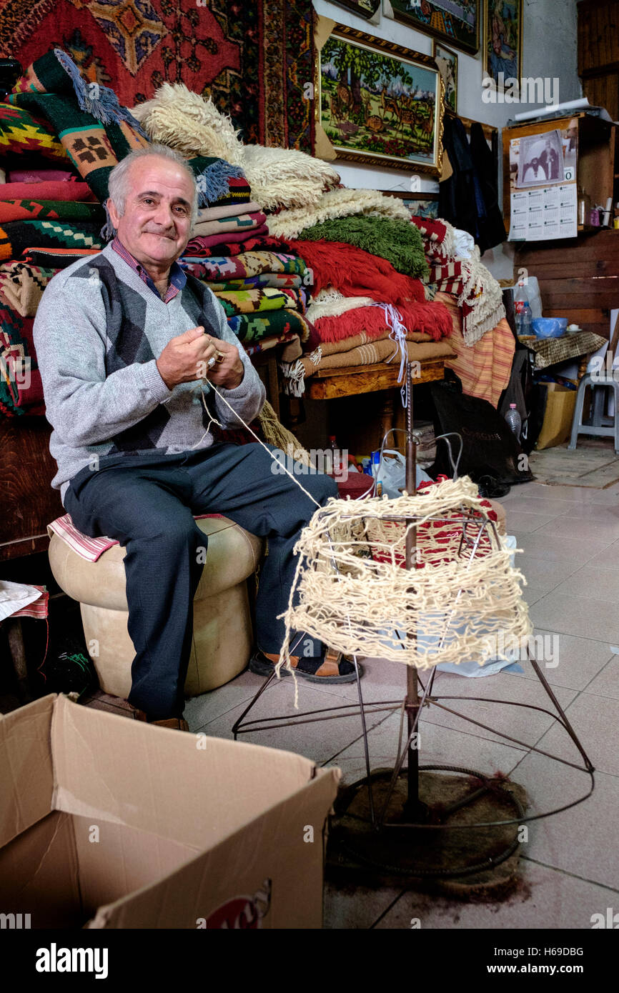 Pose d'un tisserand dans son magasin à la marché médiéval. Le marché médiéval se trouve en bas des voies étroites et pavées de Saranda, Albanie, Banque D'Images Pose d'un tisserand dans son magasin à la marché médiéval. Le marché médiéval se trouve en bas des voies étroites et pavées de Saranda, Albanie, Banque D'Images