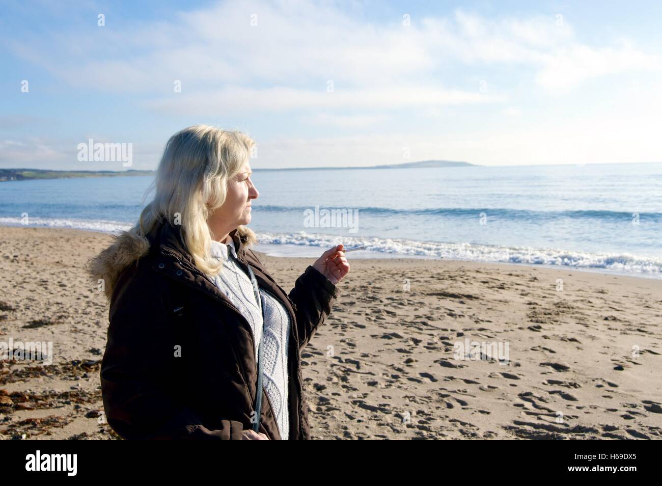 Femme de fumer une cigarette sur la plage Leven Ecosse Banque D'Images