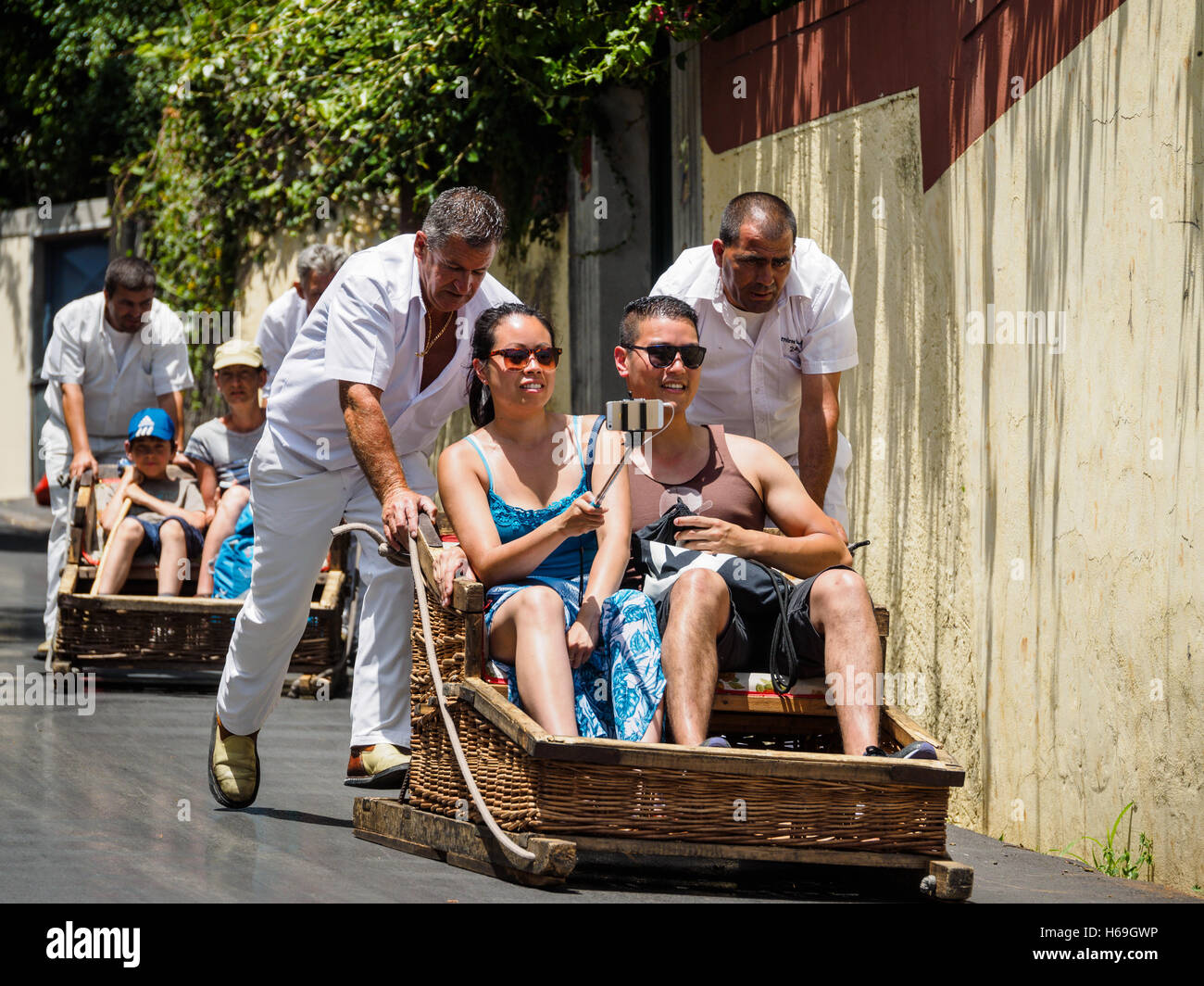 Les pilotes de luge habillé en vêtements blancs traditionnels dans les touristes un toboggan en bois en bas de la colline de Monte à Funchal Banque D'Images