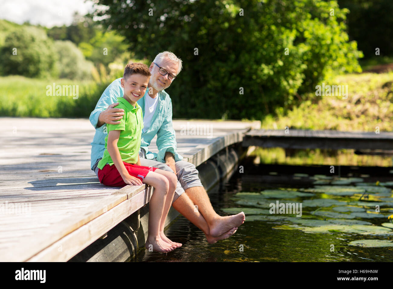 Grand-père et petit-fils assis sur le quai de la rivière Banque D'Images