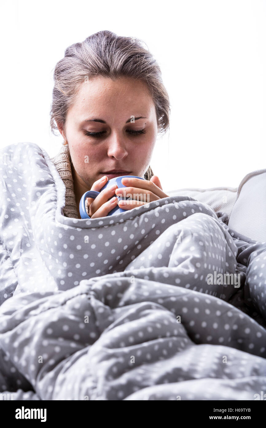 Épuisé femme est malade sur son canapé enroulée sur une couverture d'essayer de réchauffer son os à cause de cette mauvaise grippe Banque D'Images