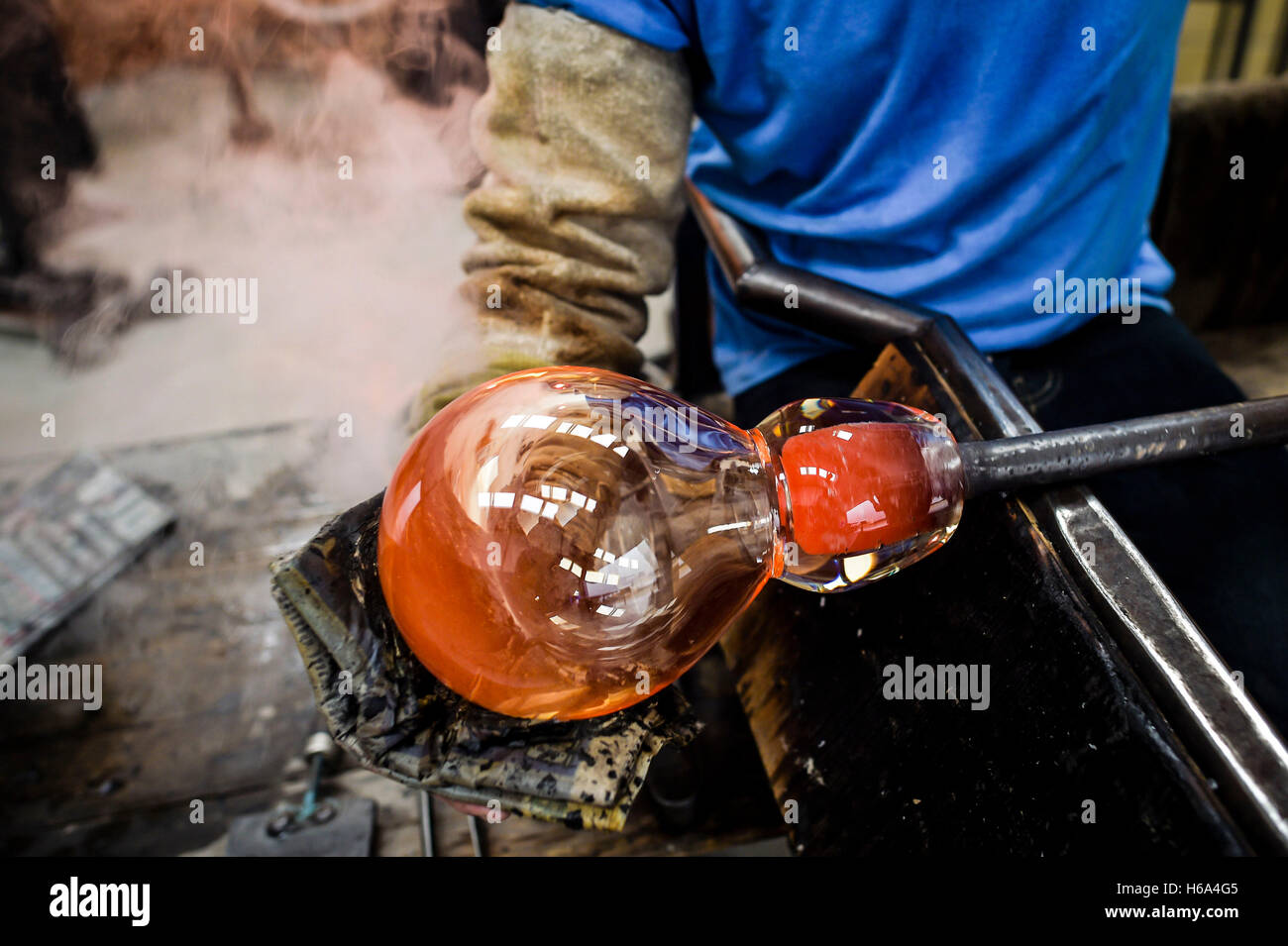 Souffleur de verre spécialiste James Devereux utilise journal humide de façonner un morceau de verre en fusion qu'il fait le verre clair cocardes pour une sculpture dans son atelier dans le Wiltshire. Banque D'Images