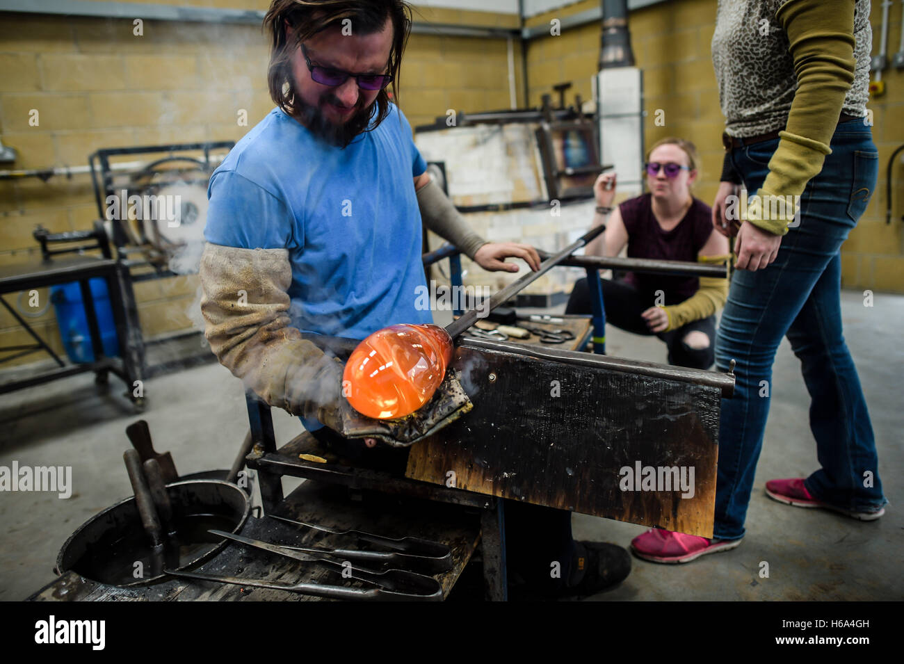 Souffleur de verre spécialiste James Devereux utilise journal humide de façonner un morceau de verre en fusion qu'il fait le verre clair cocardes pour une sculpture dans son atelier dans le Wiltshire. Banque D'Images