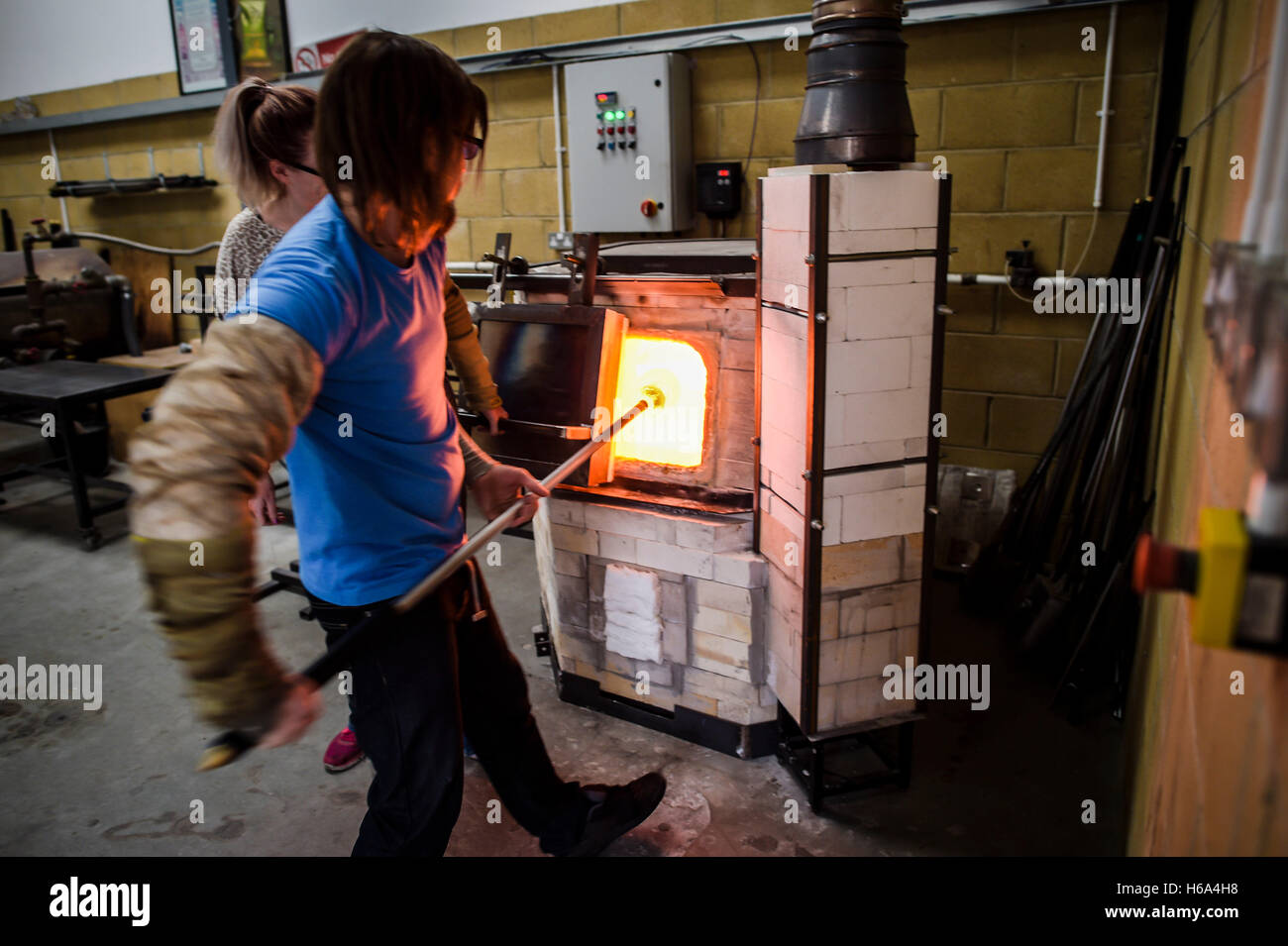 Souffleur de verre spécialiste James Devereux réunit verre en fusion d'un four pendant qu'il rend le verre clair cocardes pour une sculpture dans son atelier dans le Wiltshire. Banque D'Images