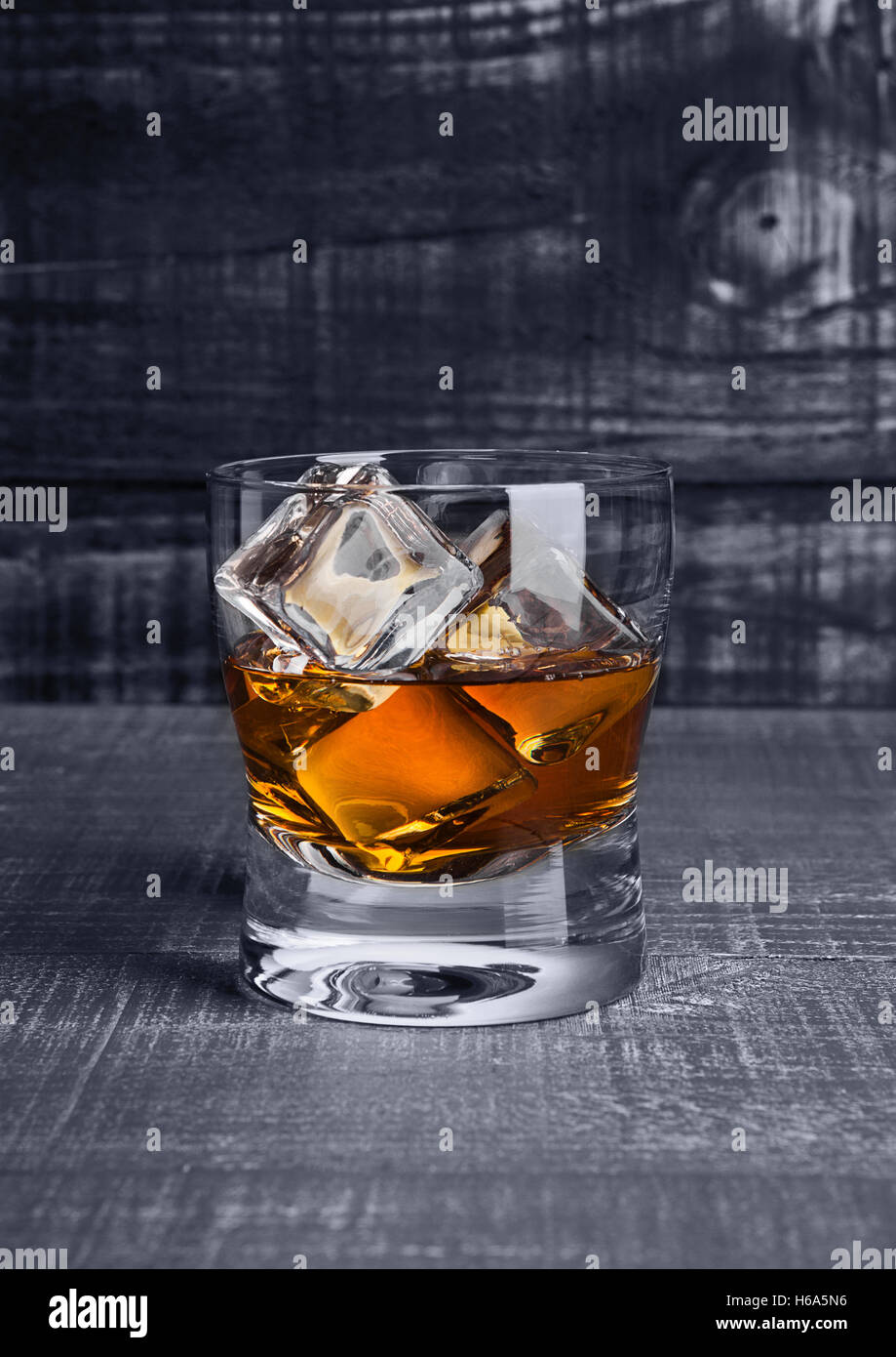 Verre de whisky avec des cubes de glace sur fond de bois bleu Banque D'Images