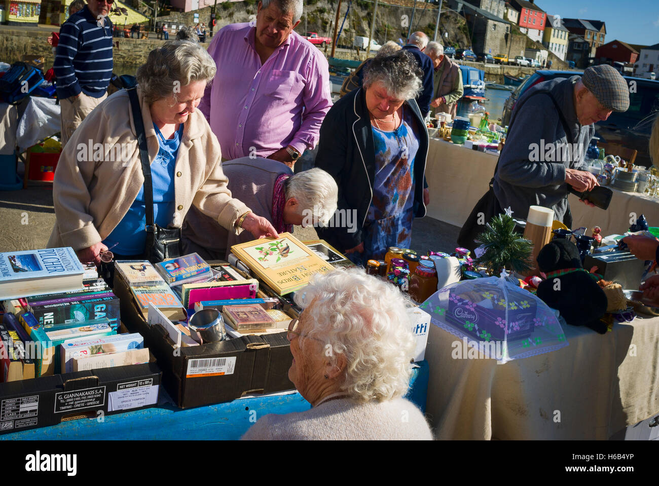 Shoppers trouver l'aubaine sur un étal de collecte de fonds de bienfaisance à Mevagissey Cornwall village UK Banque D'Images