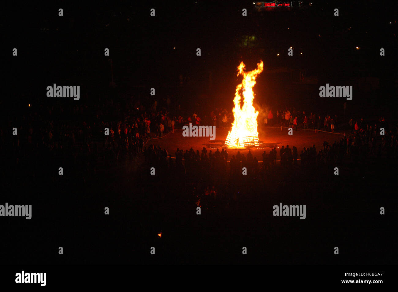 Grand feu de camp dans le noir, entouré par la foule Banque D'Images