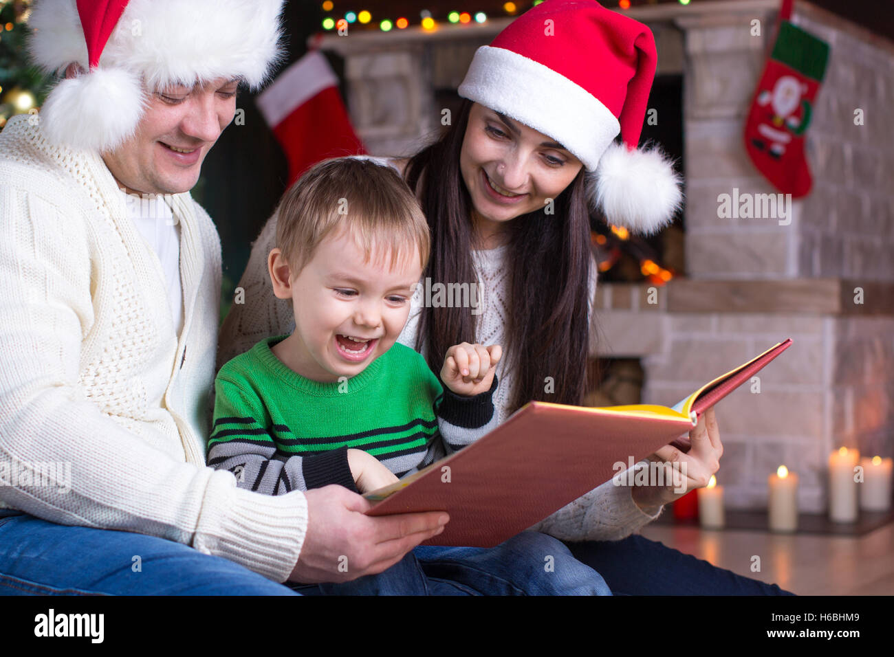 La veille de Noël de la famille par la cheminée de leur enfant livre de lecture Banque D'Images