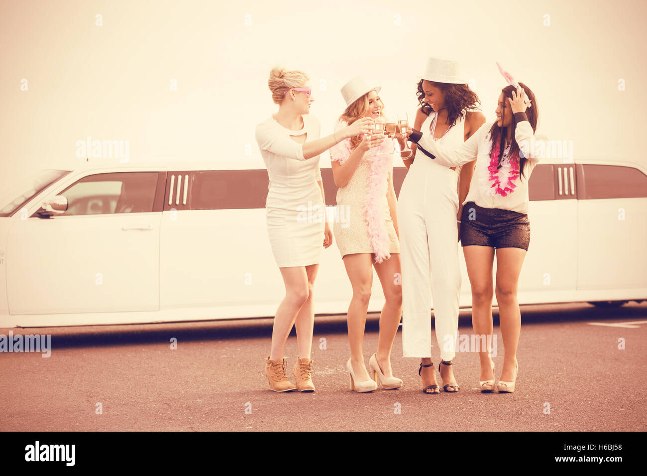 Les femmes frivoles drinking champagne à côté d'une limousine Banque D'Images