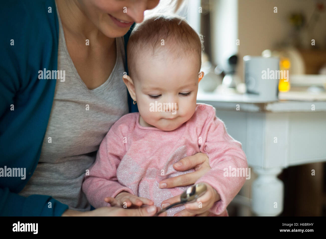 Méconnaissable jeune mère tenant sa petite fille, l'alimentation Banque D'Images