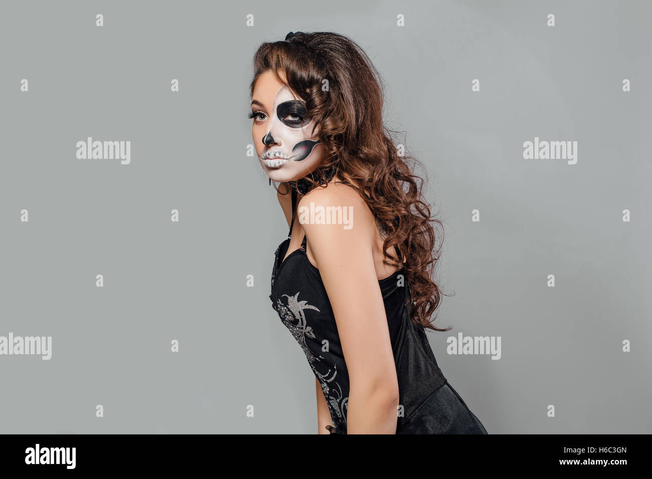 Jeune femme en noir avec la moitié du crâne face make-up. Banque D'Images