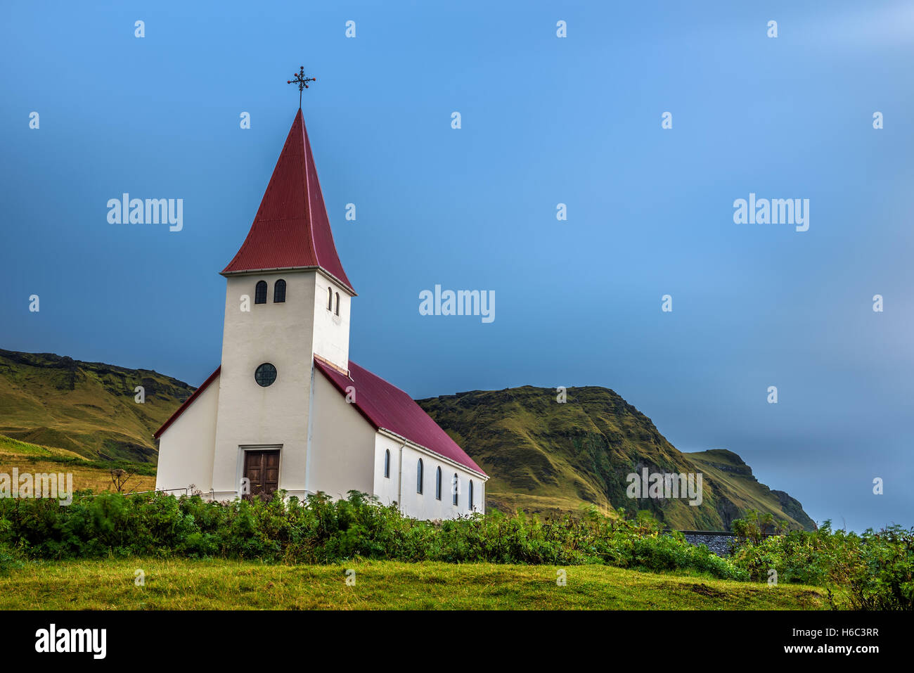 De gros nuages sur l'église luthérienne au sommet d'une montagne dans la ville de Vik en Islande. Longue exposition. Banque D'Images