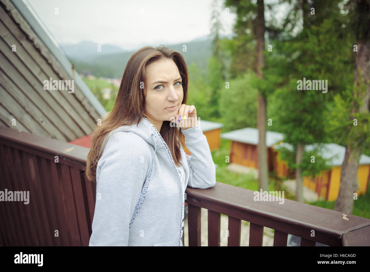Belle brune teen girl with long hair leaning on railing. Banque D'Images