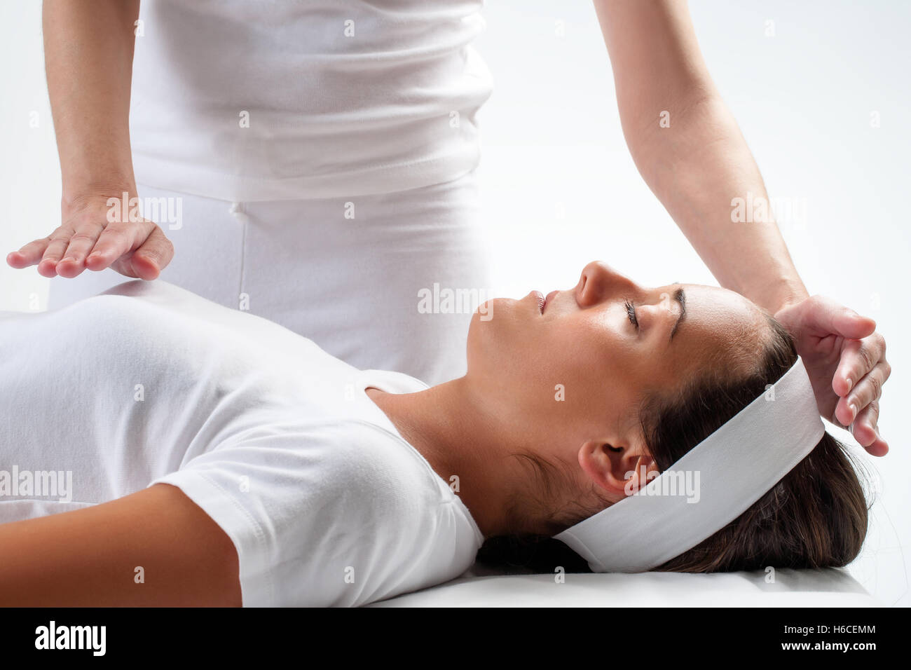 Close up of chiropractors mains faisant le reiki sur la jeune femme.Une main sur la tête et une main sur la poitrine. Banque D'Images
