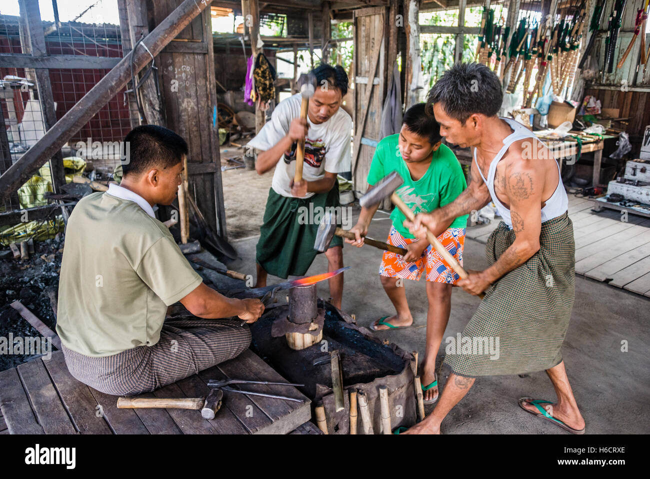 Les forgerons locaux avec des marteaux frappant sur un morceau de métal, le lac Inle, l'État de Shan, Myanmar Banque D'Images