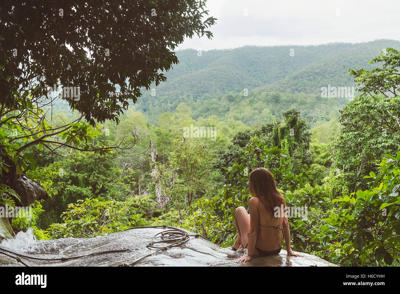 Girl in bikini assis sur le dessus d'une cascade. Banque D'Images