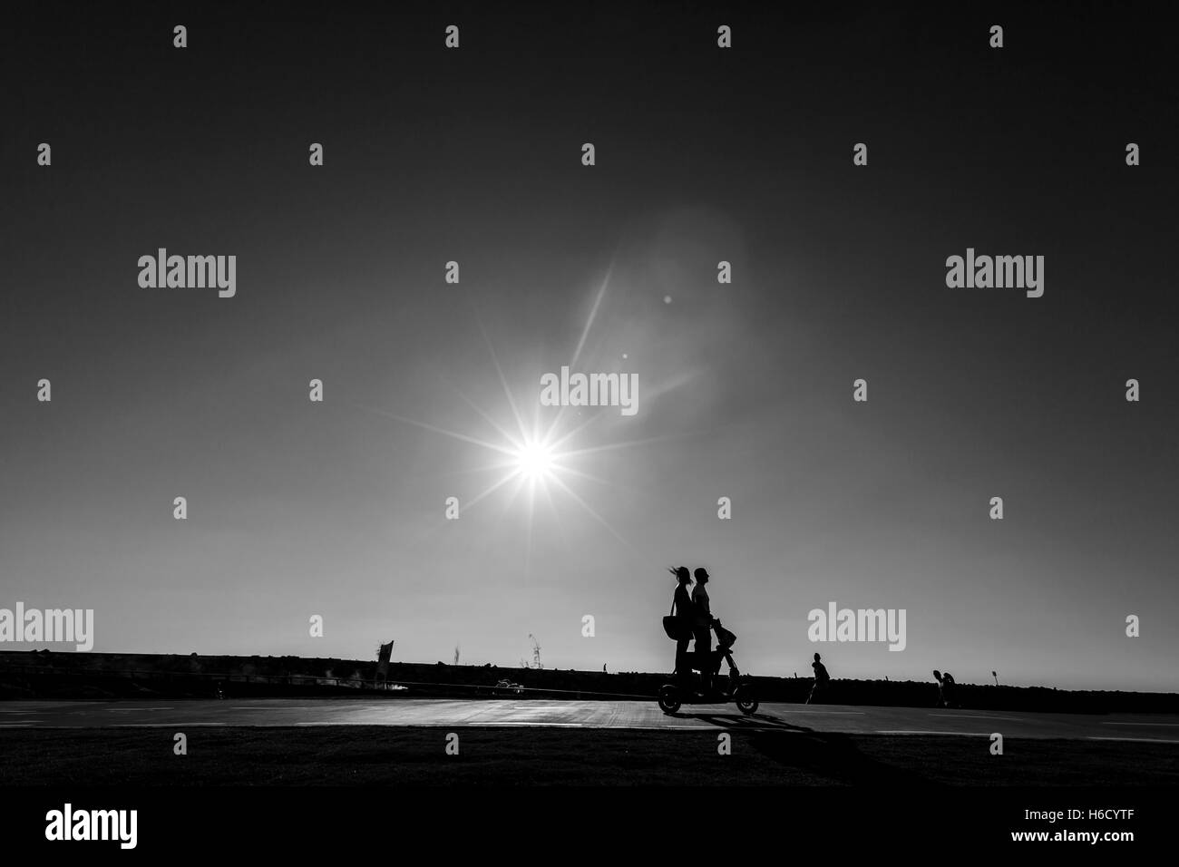Silhouette de triporteur motorisé coureurs passant sur un sentier du parc sur une claire journée d'été, soleil de l'après-midi. Banque D'Images