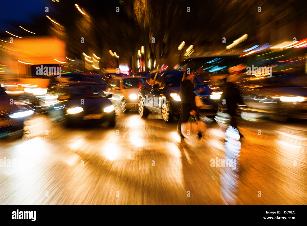 Photo avec l'appareil photo fait effet de zoom de personnes traversant une rue la nuit Banque D'Images