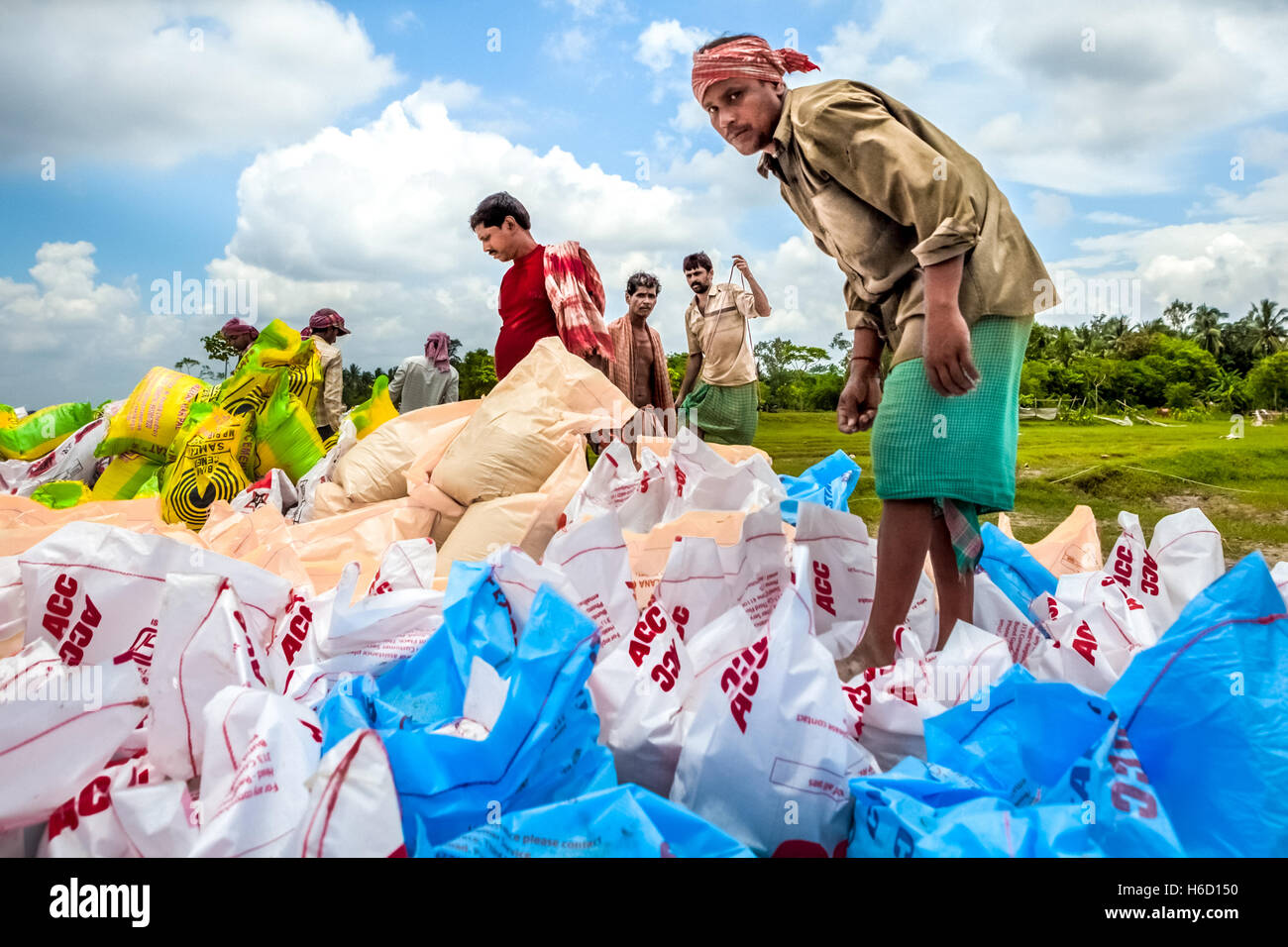 Les hommes organisent des sacs remplis de morceaux de brique pour le contrôle de l'érosion fluviale dans le Bengale occidental, Inde. Banque D'Images