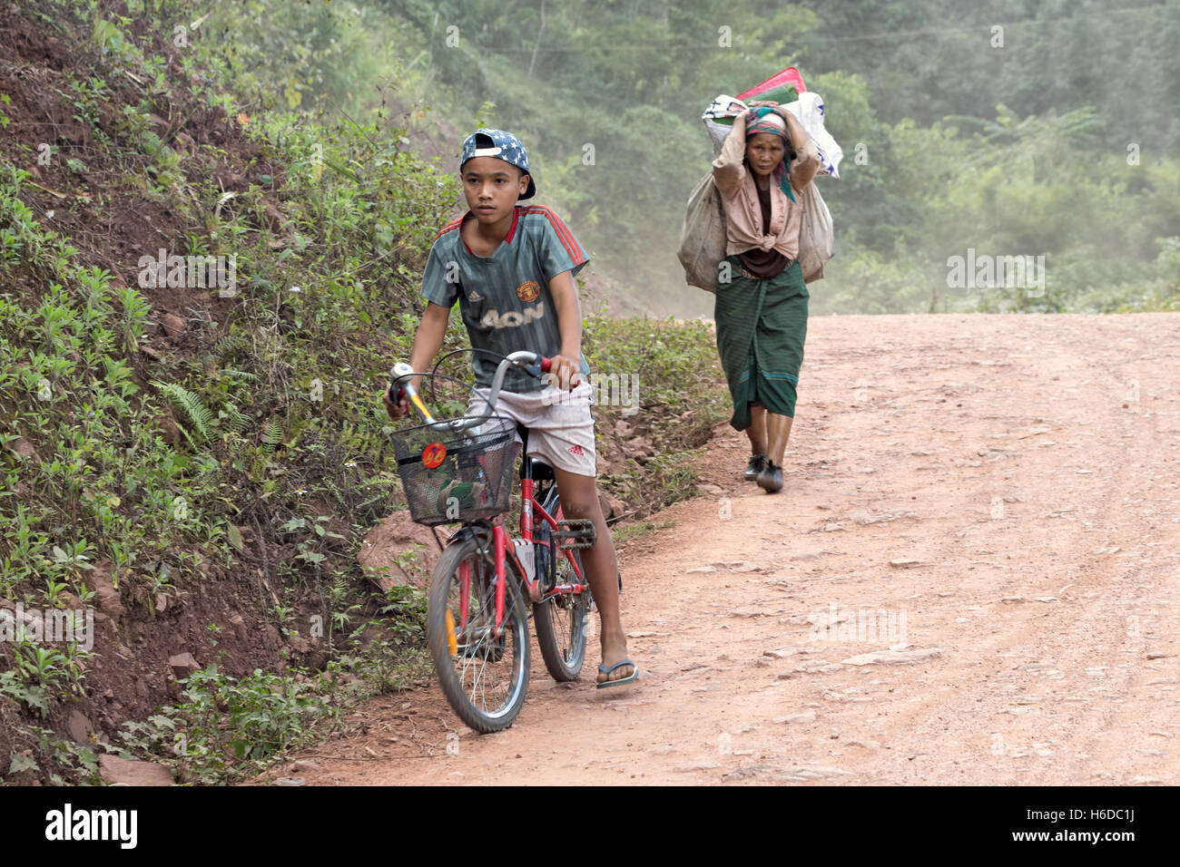 Garçon à vélo et femme âgée transportant des marchandises, village de Ban Phavie, peuple Khmu/Khamu, près de Muang la, province d'Oudomxay, Laos Banque D'Images