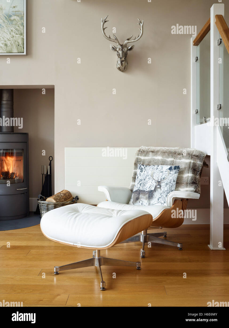Un cuir style Eames Lounge Chair et repose-pieds dans une confortable salle de séjour avec poêle à bois Banque D'Images