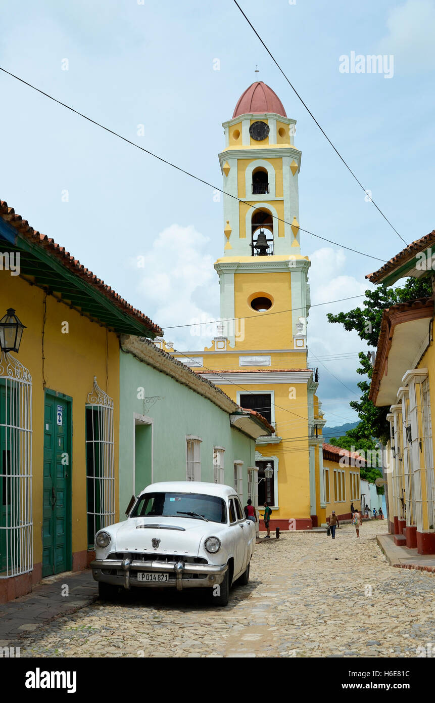 Trinidad, Cuba - 11 septembre 2015 : Rue de la Trinité, avec l'église Saint François, une voiture vintage blanc et des personnes non identifiées. Banque D'Images