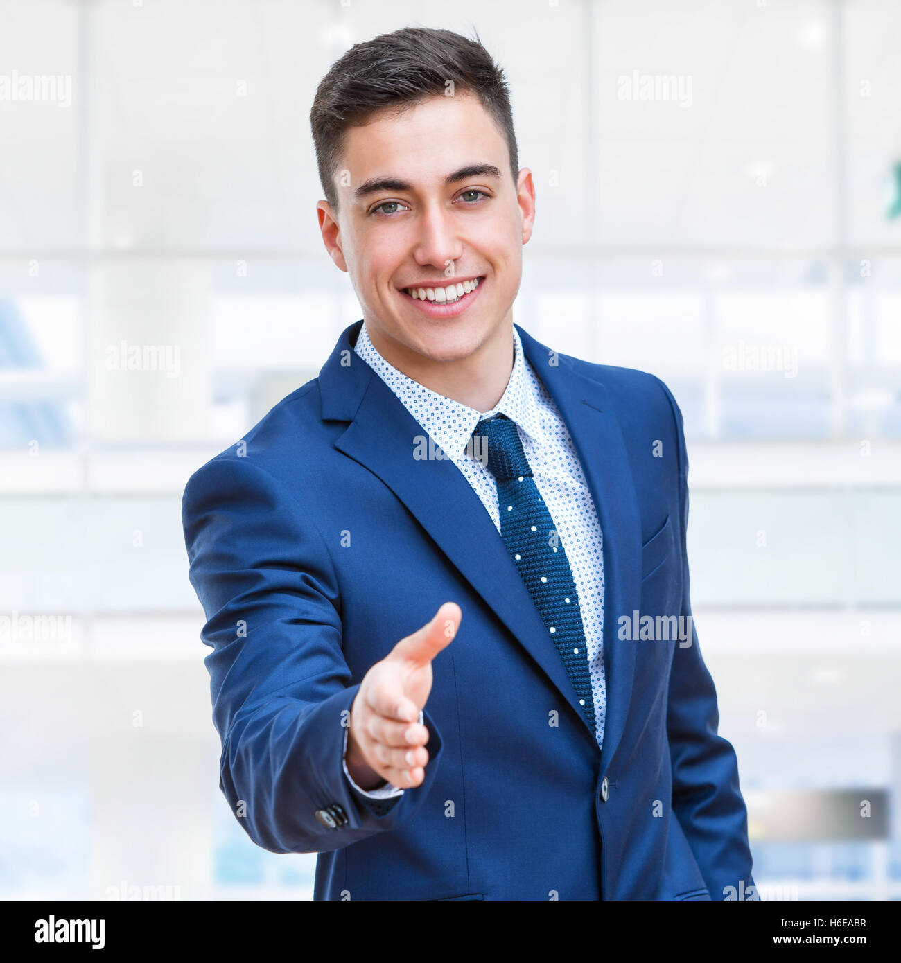 Close up portrait of young attractive Businessman reaching out suite bleue dans la main. Des problèmes de mise au point. Banque D'Images
