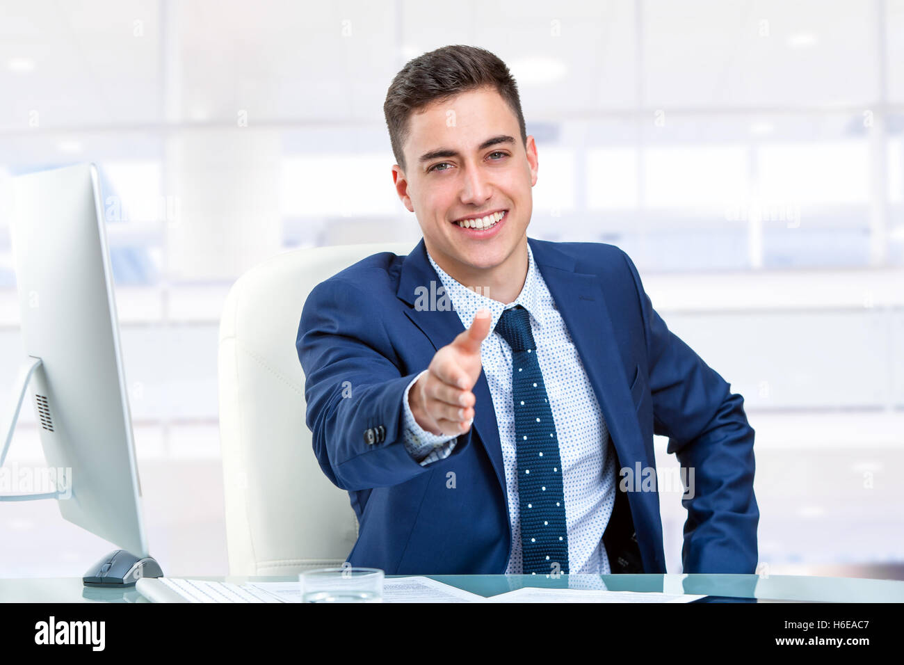 Close up portrait of handsome businessman reaching out main à 24. Jeune homme dans le bureau devant l'ordinateur. Banque D'Images