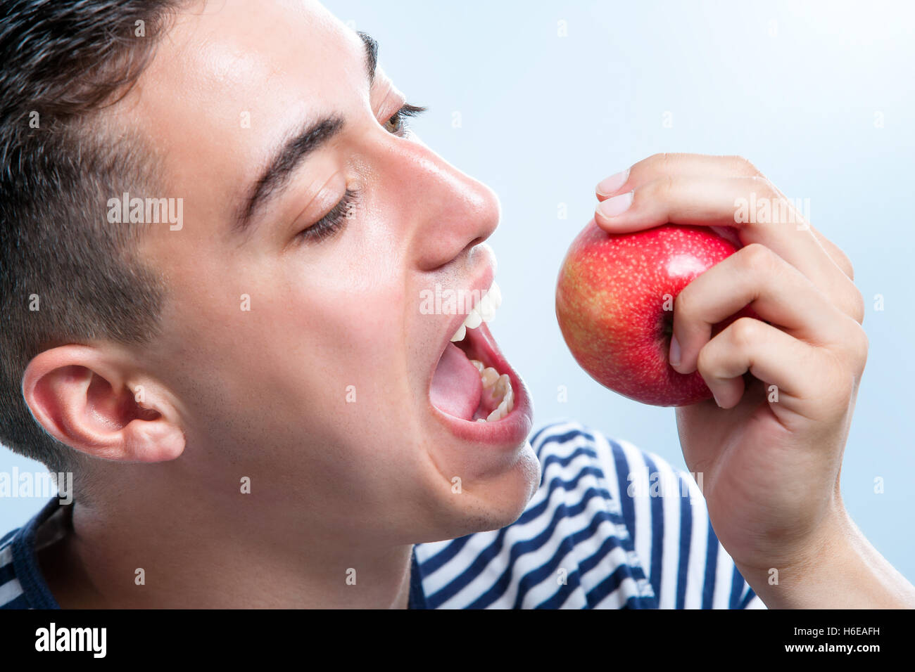 Extreme close up of male adolescent à propos de mordre une pomme rouge. Banque D'Images