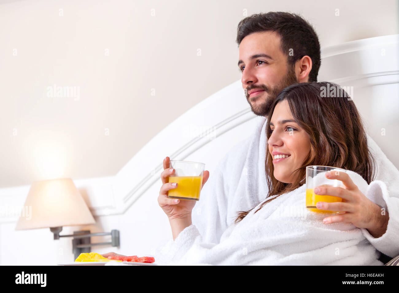 Close up portrait of couple en peignoir sur le lit de boire du jus d'orange. Banque D'Images