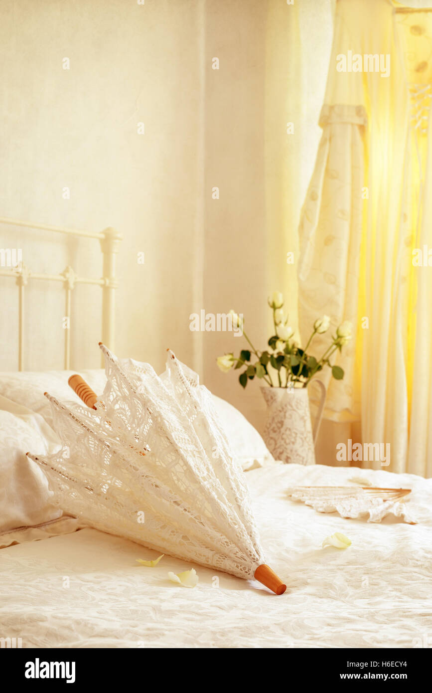 Brides parasol et ventilateur couché sur le lit avec robe de mariage pendaison dans l'arrière-plan Banque D'Images