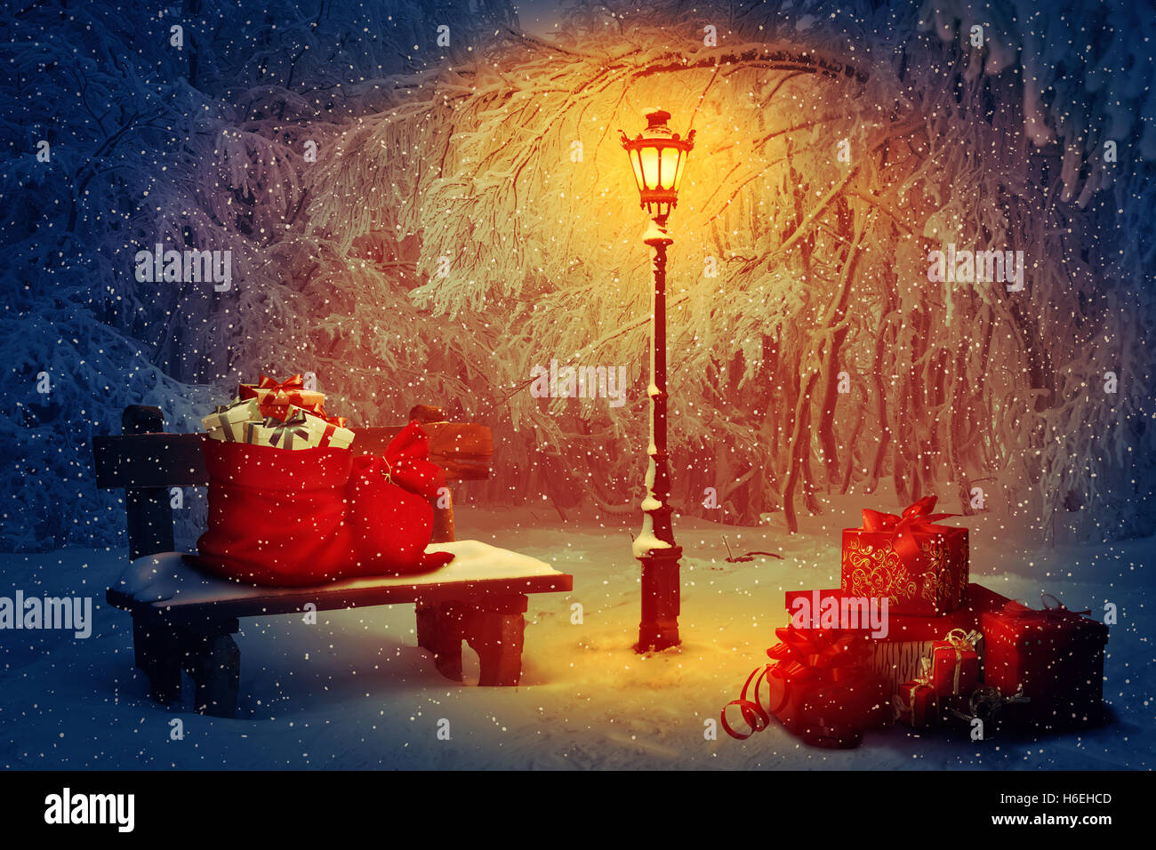 Beaucoup de cadeaux avec le Père Noël sacs dans le parc. Banc en bois et une lampe qui brille dans la nuit. Scène de Noël paisible et w Banque D'Images