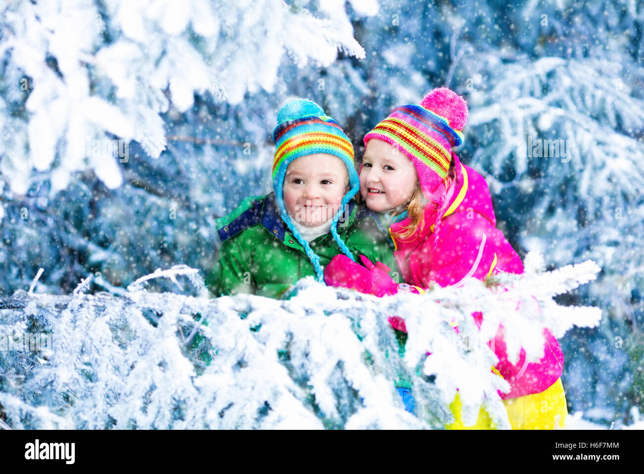 Les enfants jouent dans la forêt enneigée. Tout-petits enfants à l'extérieur en hiver. Les amis jouent dans la neige. Vacances de Noël pour la famille Banque D'Images