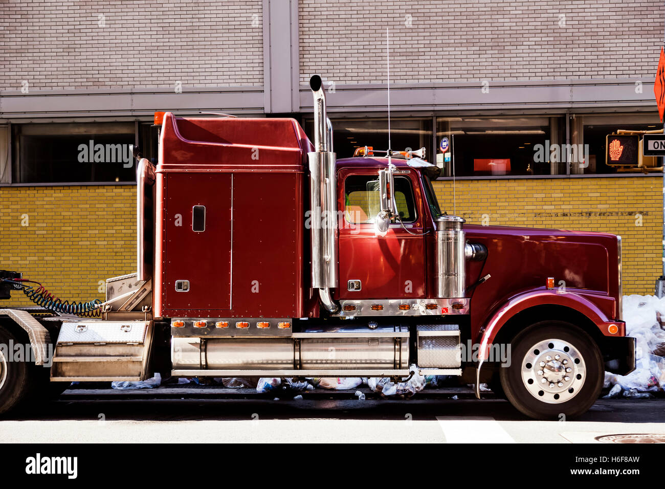 Un camion semi-remorque garé sur le trottoir avec beaucoup d'ordures derrière elle sur le trottoir. Banque D'Images