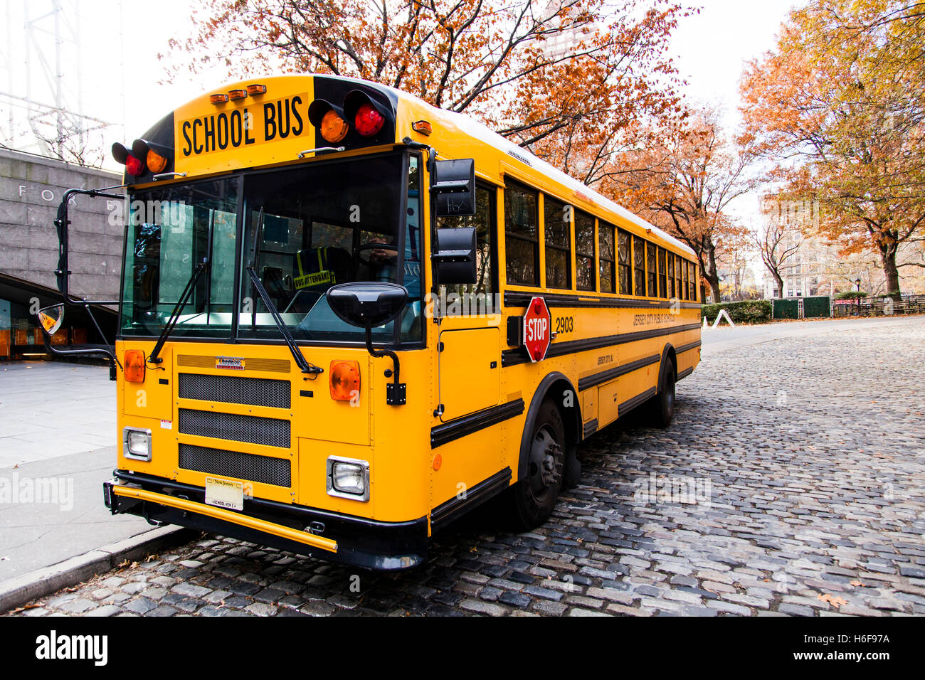 Un autobus scolaire jaune gratuit sur une vieille rue pavée de style. Banque D'Images