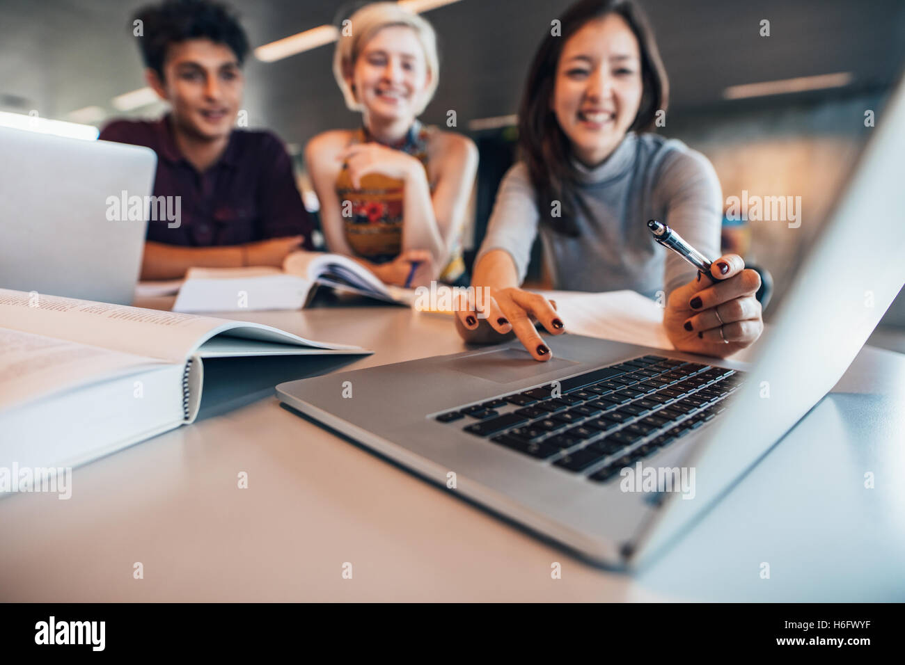 Groupe d'happy friends working on laptop in class. Étudiante avec ses camarades d'étudier ensemble et comput looking at laptop Banque D'Images