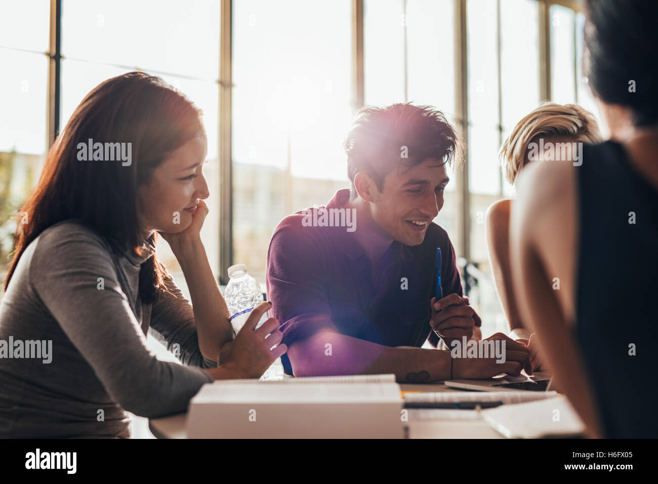 Jeune homme avec des camarades de classe utilisant un ordinateur portable en classe. étudiants universitaires travaillant sur ordinateur portable et souriant. Banque D'Images