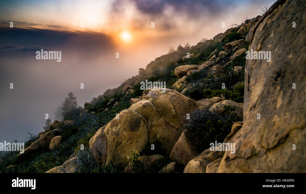 Coucher du soleil sur le flanc d'une montagne avec une personne assise sur un rocher dans la distance. Santa Barbara, Californie. Banque D'Images