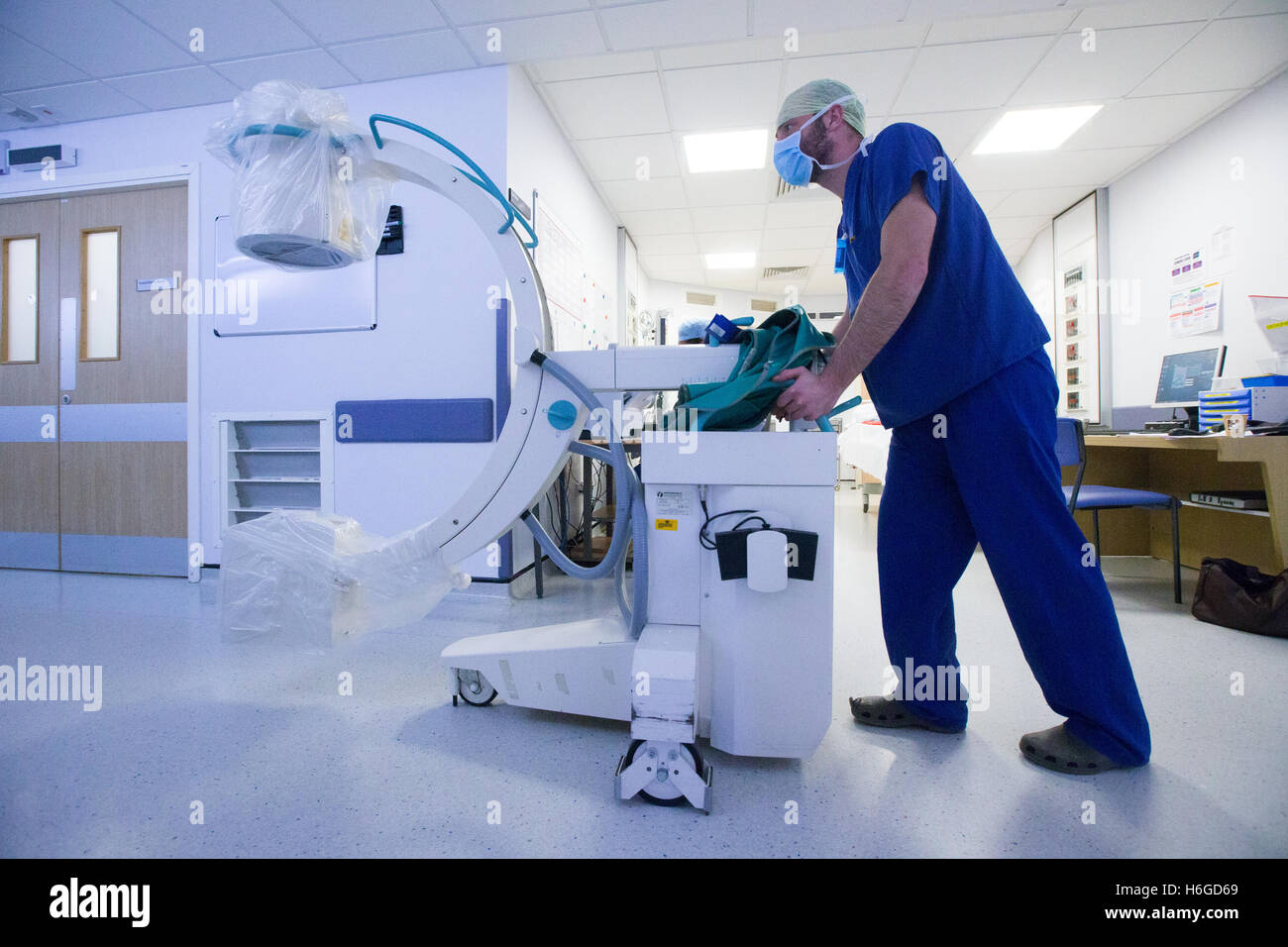 Un technicien de l'hôpital une machine à rayons X pousse le long d'un couloir Banque D'Images