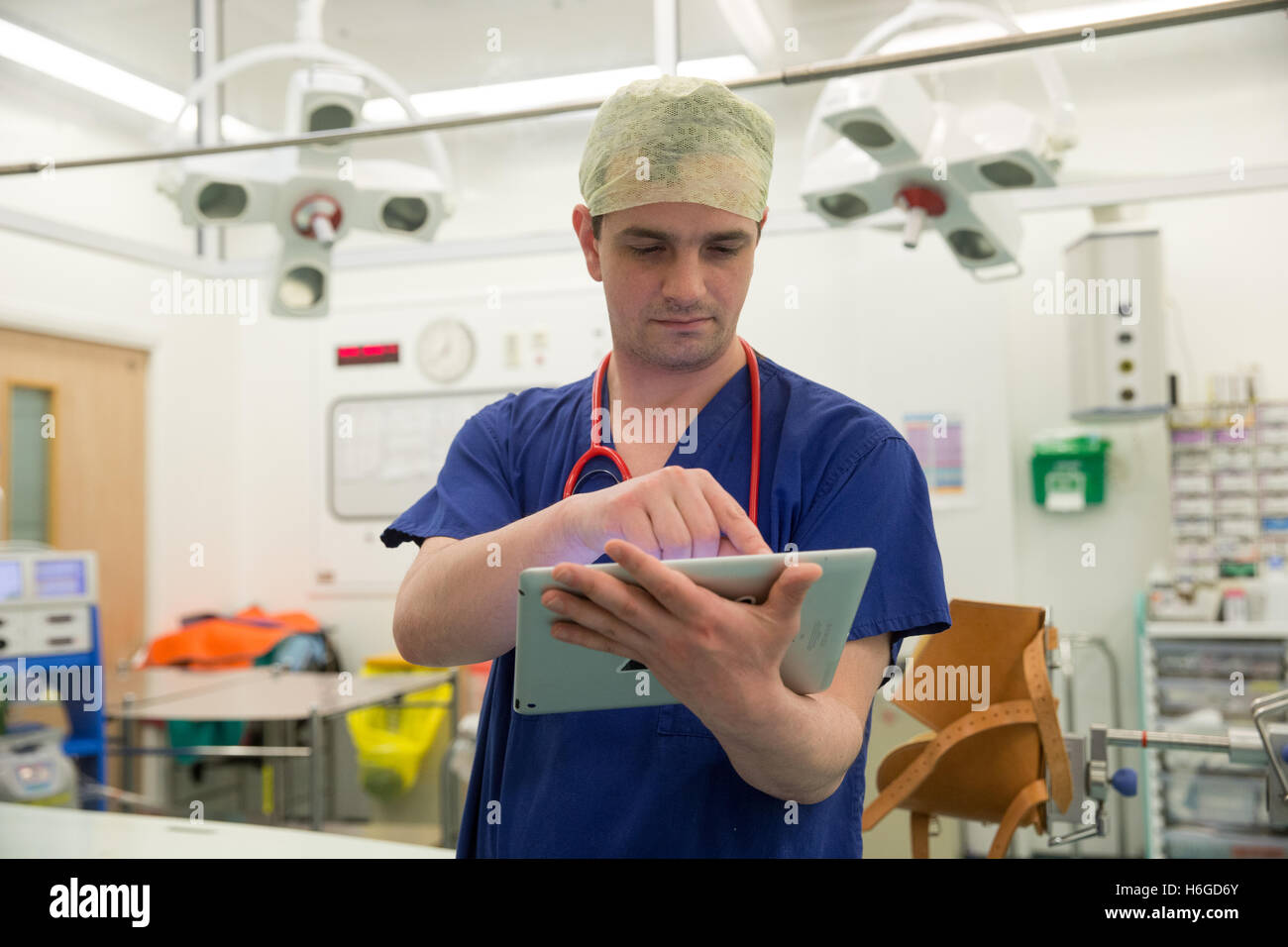 Un chirurgien dans un hôpital d'opération vérifie les notes des patients sur son Ipad avant d'une opération Banque D'Images