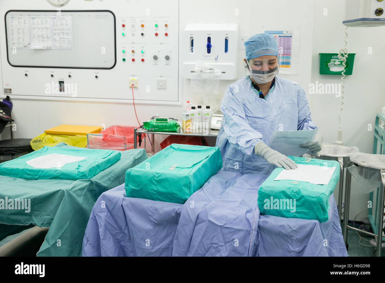 Une infirmière de l'hôpital dans scrubs vérifie le matériel stérile avant de les ouvrir dans un théâtre d'opération des hôpitaux Banque D'Images