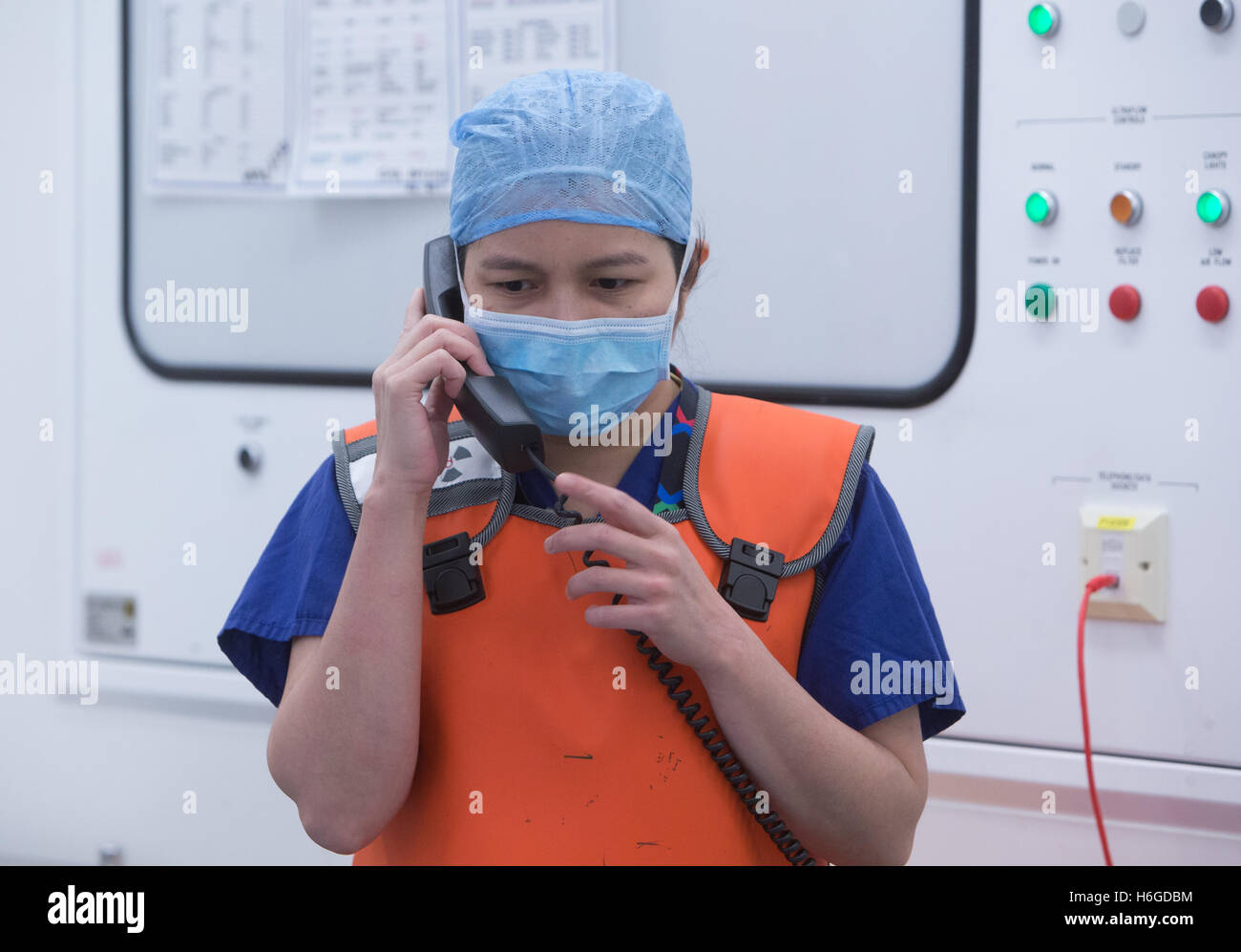 Une infirmière dans scrubs vérifier une Les dossiers des patients sur le téléphone dans un théâtre d'opération des hôpitaux au cours d'une opération Banque D'Images