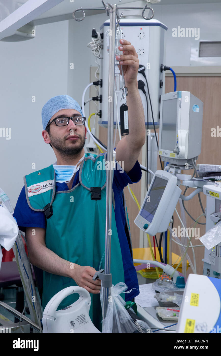 Un anesthésiste vérifie une goutte médical au cours d'une opération dans un hôpital Theatre Banque D'Images