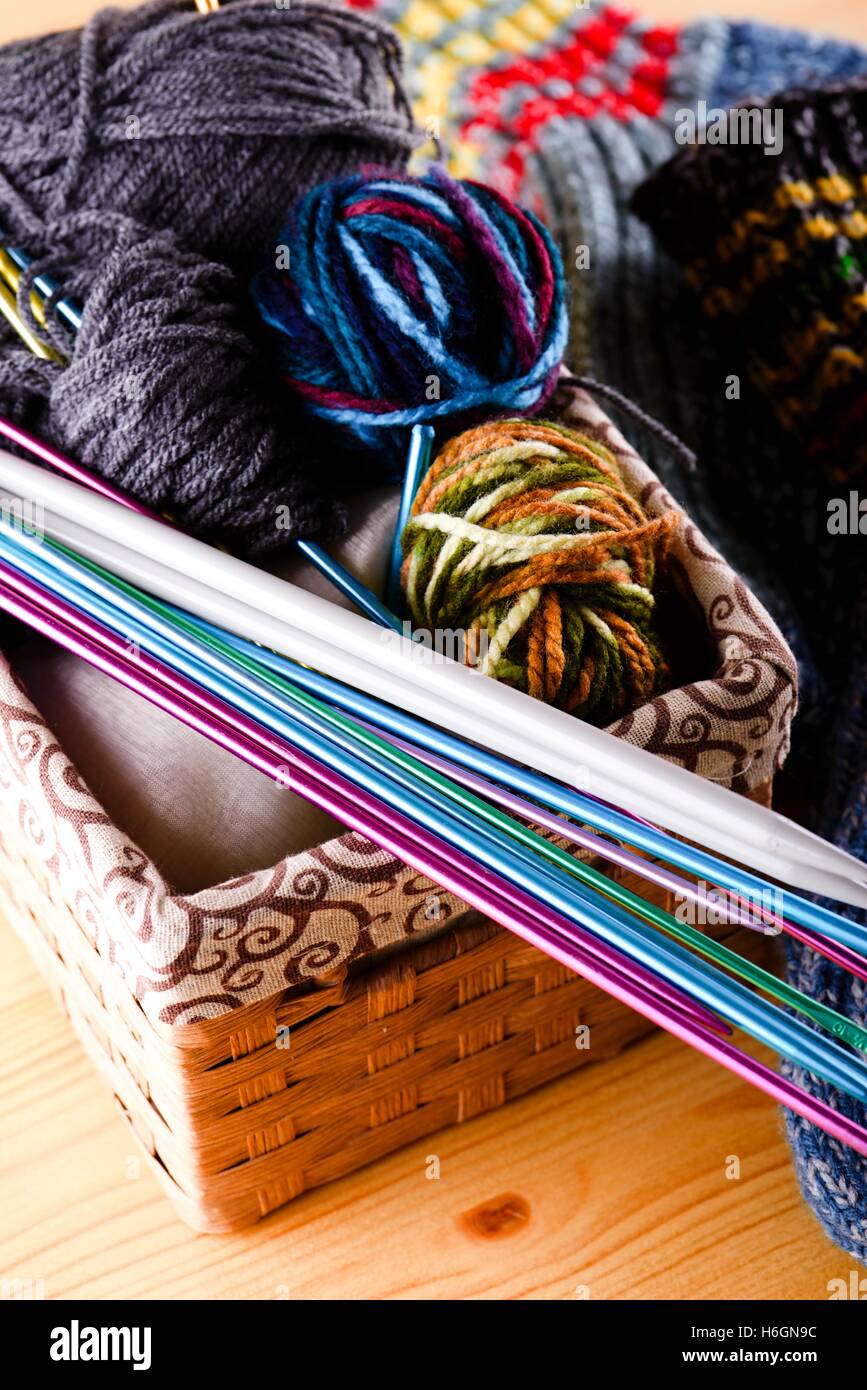 Photo verticale de boîte pleine de différents indices de laine couleur avec plusieurs aiguilles à tricoter qui sont placés sur le coin. Fort est sur l Banque D'Images