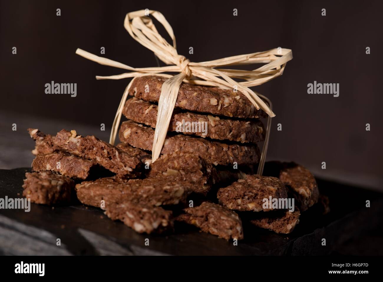 Photo horizontale de plusieurs biscuits céréales placés dans une pile de stockage de paille jaune placé sur le morceau de pierre noire. Peu de casse Banque D'Images