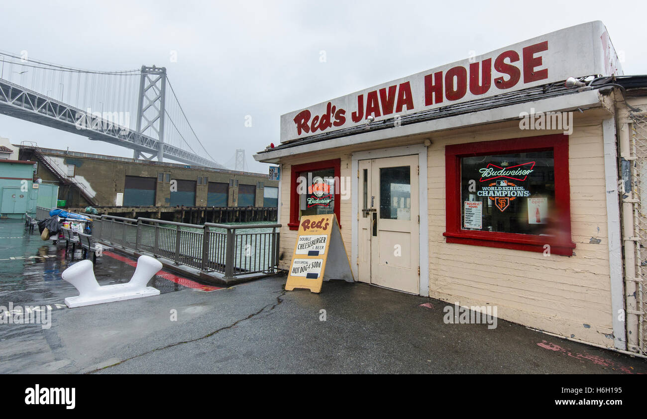 La Maison Rouge Java, sur l'Embarcadero à San Francisco, se trouve sous la pluie avec le Bay Bridge dans le fond. Banque D'Images