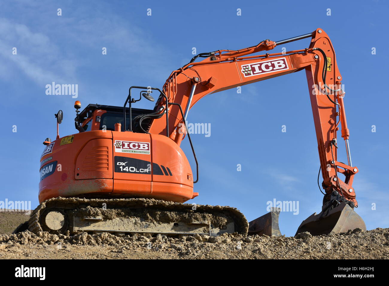 Bic rouge digger montrant les détails de l'hydraulique et de boue sur les voies. Banque D'Images