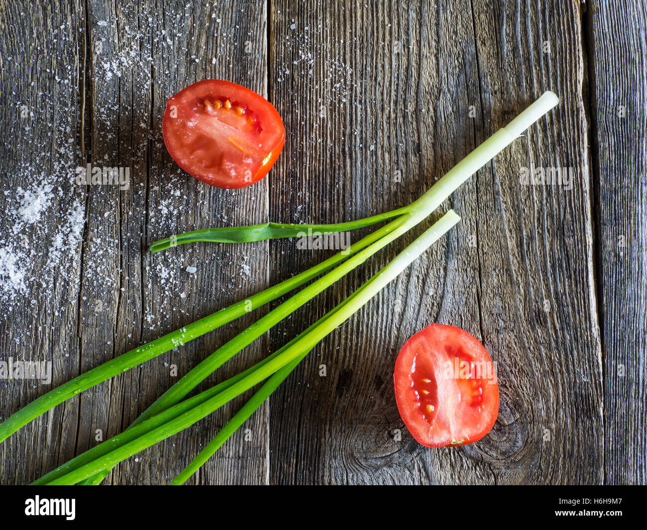 Les tomates avec les oignons verts sur fond de bois Banque D'Images