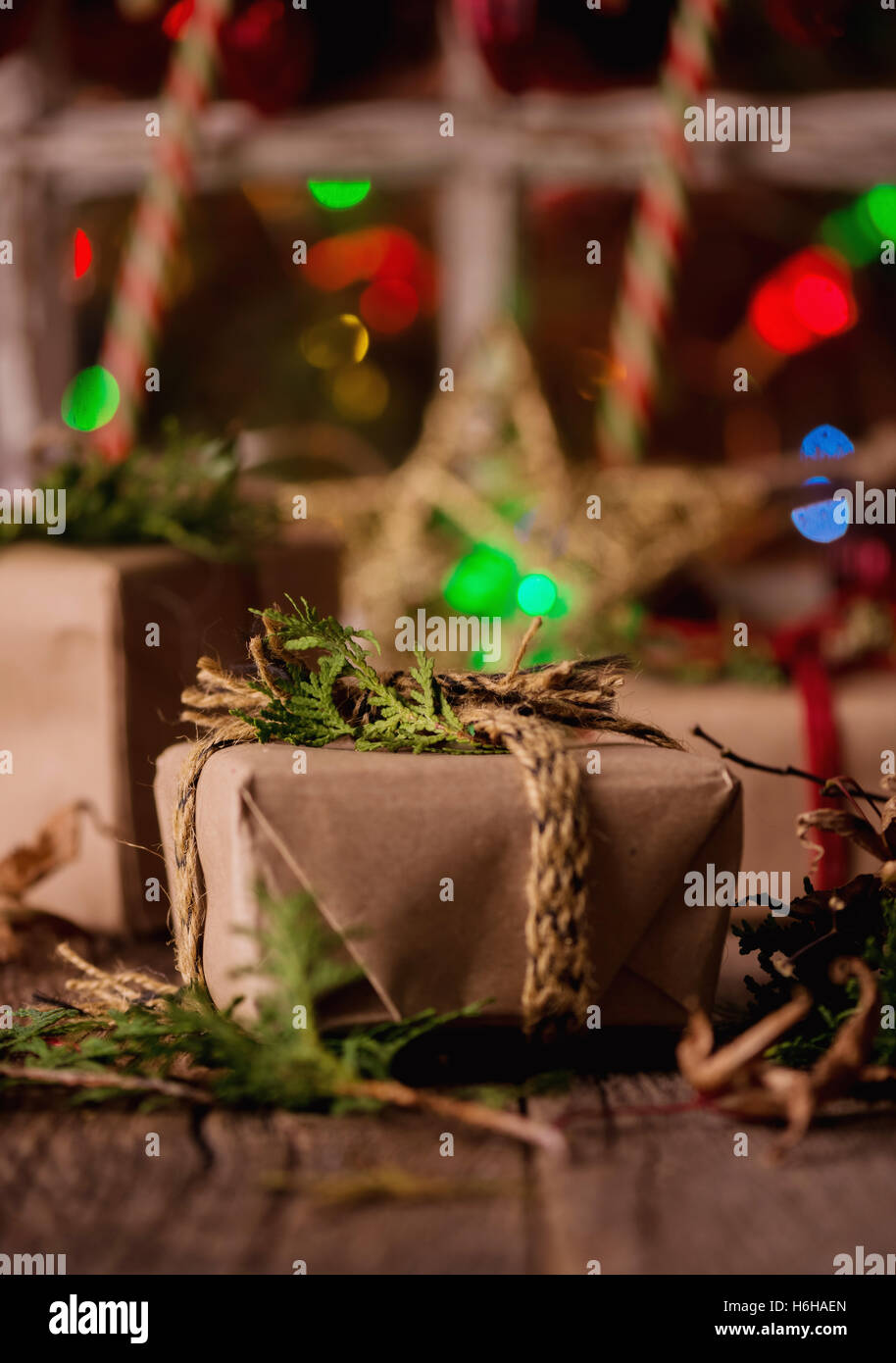 Cadeaux de Noël enveloppé rustique contre fenêtre avec lumières Banque D'Images