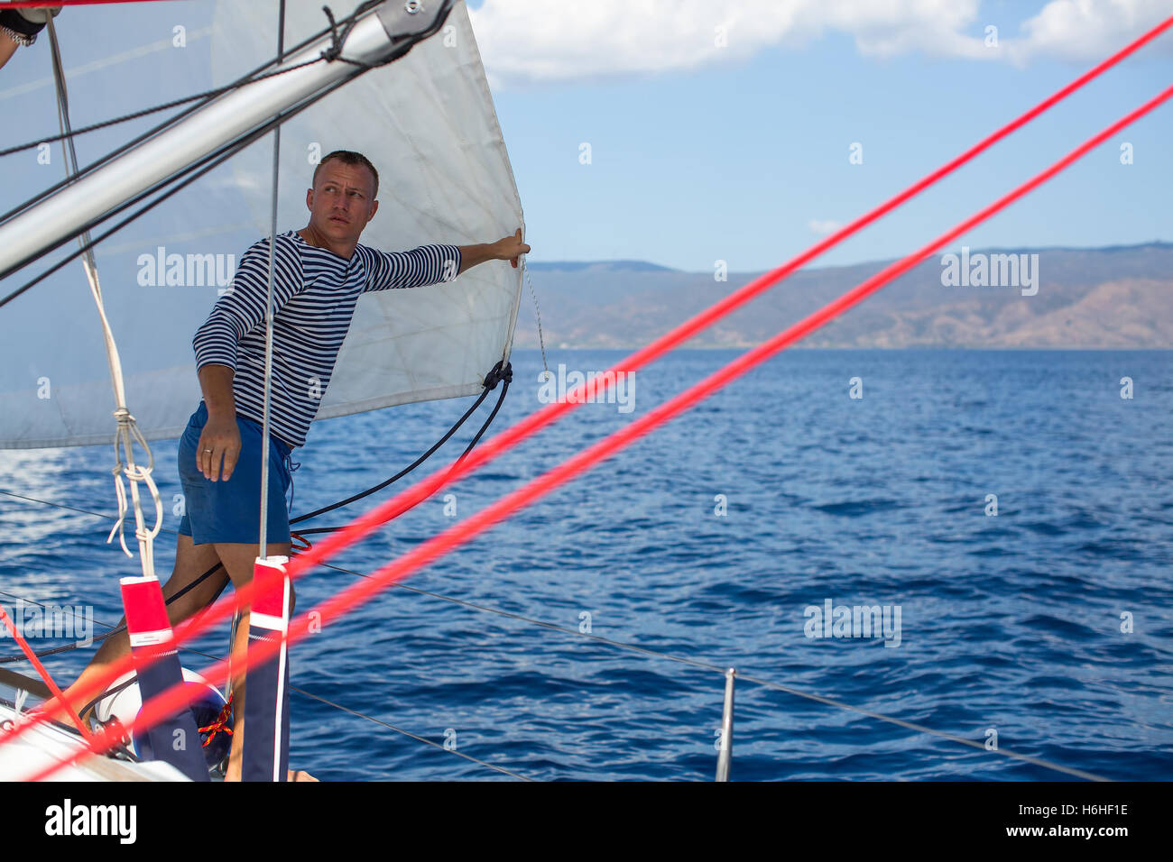 Jeune homme skipper - réglage de voiles sur le yacht à voile. Location, vacances, voyage. Banque D'Images